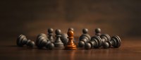 Wooden chess pawn in gold standing out among gray pieces on board, symbolizing leadership, strategy, uniqueness and competitive advantage in business.