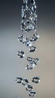 Crystal clear water bubbles floating and falling through air with sparkling light reflections creating dynamic motion against gradient background.