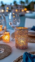 Romantic outdoor table setting with glowing candle holders, wine glasses and woven placemats against blurred evening lights background. Perfect for wedding decor.