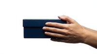 Hand holding dark blue rectangular gift box against white background isolated for design and commercial use.