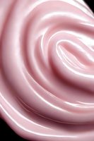 Soft pink swirling abstract background with gentle curves and light effects creating elegant rose-like pattern against dark backdrop. Suitable for luxury product marketing.