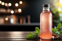 Fresh pink lemonade in glass bottle with condensation drops, mint leaves on rustic wooden table against blurred bokeh lights background. Summer drink concept.