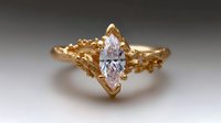 Marquise cut diamond engagement ring in organic textured gold setting with nature-inspired details and unique branch-like design elements creates romantic appeal.