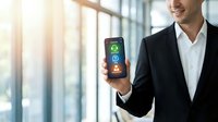 Professional businessman displaying smartphone with colorful app interface in modern office environment with natural lighting and glass windows.
