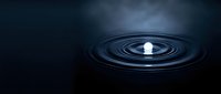 Water drop creating ripples on dark surface with dramatic lighting and reflections for abstract concepts and meditation themes.