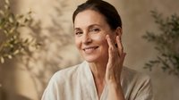 Mature woman applying skincare cream to face in spa setting, anti-aging beauty routine, wellness and self-care concept for cosmetic advertising.