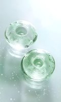 Round glass containers with water drops on mint green background, creating fresh minimalist composition with bubbles and reflective surfaces.