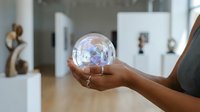 Professional woman holding glowing digital sphere with network connections in modern office environment showcasing future technology and innovation.