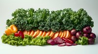Fresh organic vegetables arranged in row including curly kale, carrots, red onions and lettuce on light background. Clean eating and healthy food concept.