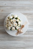 Elegant white roses in round gift box with beige ribbon on rustic wooden background, perfect for wedding or anniversary.