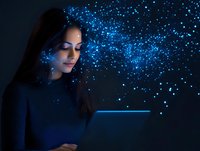 Young woman with long dark hair using digital tablet in dark room with magical blue light particles and sparkles creating ethereal atmosphere.