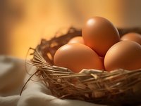 Fresh brown eggs nestled in natural straw nest against warm golden background, soft focus composition highlighting organic farm-to-table concept.