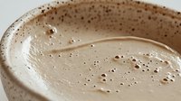 Creamy chocolate milkshake with frothy bubbles in ceramic cup, close up view showing smooth texture and rich brown color. Perfect for food and beverage marketing.