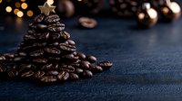 Roasted coffee beans arranged in Christmas tree shape on dark background with bokeh lights and copy space. Creative holiday food concept.