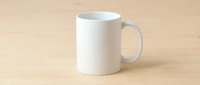 White ceramic coffee mug on wooden table surface ready for custom design printing and branding mockup template for promotional merchandise.