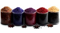 Colorful spice powders in metal containers with star anise, featuring vibrant red, purple, brown and golden seasonings for culinary cooking and food preparation.