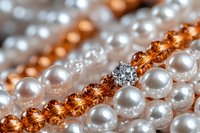 Elegant white pearls and copper-colored beads with sparkling diamond accent in macro photography, creating luxurious jewelry composition with soft focus effect.