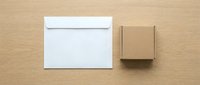 White envelope and brown cardboard box on wooden surface for shipping and packaging mockup design projects.