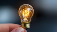 Glowing vintage light bulb with golden glitter sparkles on blurred background, creative innovation concept for business and technology solutions.
