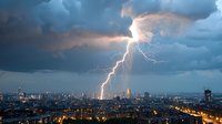 Dramatic lightning bolt strikes urban cityscape during stormy sunset, illuminating dark clouds above metropolitan skyline with glowing streets and buildings below.
