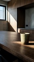 Minimalist wooden desk with ceramic cup in modern interior space with natural sunlight, concrete walls, and wood paneling for contemporary design projects.