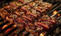 Juicy beef kebabs with spices grilling on barbecue grate over hot coals, showing grill marks and caramelization. Close up view captures sizzling meat texture.
