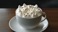 White coffee cup with whipped cream topped with heart-shaped marshmallows on wooden table, romantic hot beverage for Valentine's Day celebration.