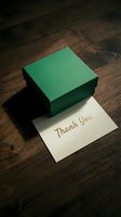 Green gift box with gold thank you card on dark wooden surface, elegant gratitude concept for holidays, celebrations, and appreciation.