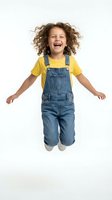 Joyful mixed-race child with curly hair jumping in denim overalls and yellow shirt isolated on white background for design projects.
