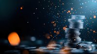 Stacked silver coins with magical sparkles and orange bokeh lights on dark background, financial growth concept for business and investment planning.