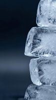 Stacked ice cubes with crystalline texture and frost formations against a dark blue background, suitable for beverage, cooling, and refreshment concepts.