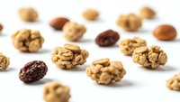 Mixed nuts and dried fruits scattered on white background for healthy snacking and cooking ingredients.