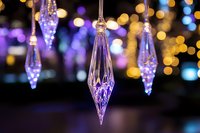 Crystal teardrop ornaments hanging with warm bokeh lights creating magical holiday atmosphere for festive decorations and seasonal celebrations.
