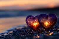 Two glowing heart-shaped lanterns on pebble beach at sunset create romantic atmosphere for Valentine's Day celebration and love concepts.