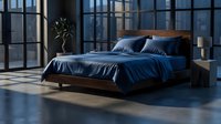 Modern minimalist bedroom with dark blue bedding and wooden platform bed frame in industrial loft space with large windows and natural lighting.