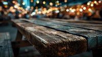 Rustic wooden table surface with warm bokeh lights creating cozy atmosphere for product placement and food photography backgrounds.