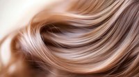 Flowing strands of silky blonde and brown hair create smooth waves against light background, showcasing natural movement and shine for beauty and haircare marketing.