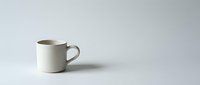 Simple beige ceramic coffee mug on clean white background, minimalist kitchen tableware for morning beverage, isolated product shot for design projects.
