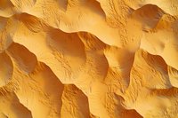 Abstract aerial view of golden sand dunes creating natural patterns and textures in desert landscape. Dramatic shadows and ridges form flowing curves and ripples.