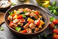 Grilled salmon chunks with colorful bell peppers, fresh herbs and vegetables in rustic ceramic bowl. Mediterranean style healthy dinner served with basil leaves.