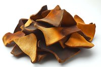 Dried mushrooms heap isolated on white background, organic food ingredients. Brown dehydrated wild forest mushroom pieces for cooking and seasoning.