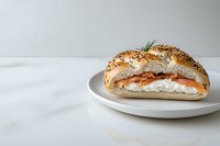 Fresh bagel sandwich with smoked salmon, cream cheese, and everything seasoning on white plate against marble background. Perfect for food blogs and menus.