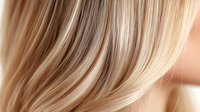 Silky smooth blonde hair strands flowing in gentle waves, close-up view showing natural highlights and texture. For beauty, fashion and hair care advertising.