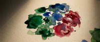 Colorful acrylic paint blobs in red, blue and green mixed on artist palette creating vibrant artistic mess for creative painting projects and art education.