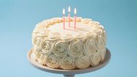 Birthday cake with vanilla buttercream roses and three pink candles on blue background for celebration party dessert baking sweet treat anniversary.