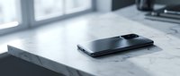 Modern black smartphone lying flat on white marble kitchen countertop surface near window with natural lighting for technology and lifestyle concepts.