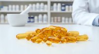 Omega-3 fish oil capsules on pharmacy counter with pharmacist in background. Dietary supplements and healthcare concept for wellness industry.