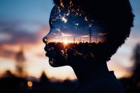 Double exposure silhouette of African American woman profile merged with urban sunset skyline and power lines, creating dreamy atmospheric mood against blue and orange sky.