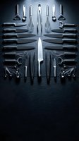 Professional kitchen utensils and knives arranged symmetrically on dark slate surface for culinary design and restaurant branding projects.