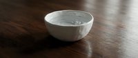 White ceramic bowl with water on dark wooden surface, suitable for kitchenware, tableware, and home decor design projects.
